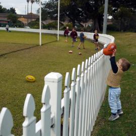 Little boy with football by the fence at Jubilee Oval, Glebe, 2017