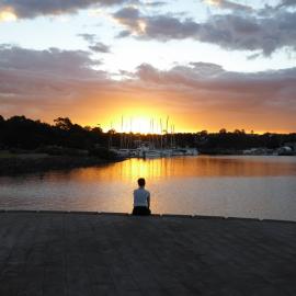 Woman seated on the water's edge at Bicentennial Park, Glebe, 2019