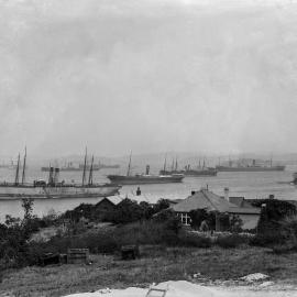 View of merchant marine ships from shore with huts in foreground, possibly Cockatoo Island, no date