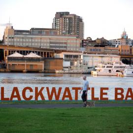 Man walking his dog in front of Blackwattle Bay signage, 2015