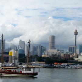 'Tribal Warrior' moored in Blackwattle Bay with view of Sydney city skyline behind, 2009