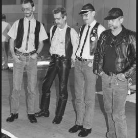 Four men examining banner at the AIDS Memorial Quilt Project, circa 1992