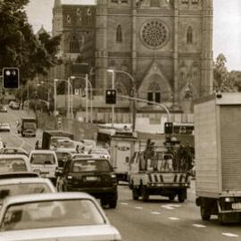 Traffic and St Mary's Cathedral spire under construction, College Street Sydney, 1998