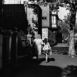 Woman and girl walking along an unidentified street in Surry Hills, 1976