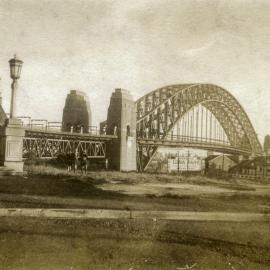 Three boys standing before the Sydney Harbour Bridge, Dawes Point Reserve, 1943