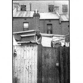 Young girl climbing backyard fence, Glebe, 1973