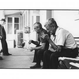 Elderly men smoking on bench at Hospital Annex