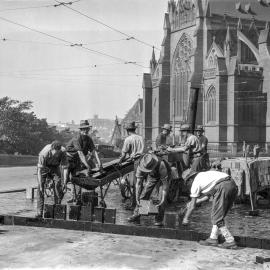 Men woodblocking the road outside St Mary's Cathedral, College Street Sydney, 1930s