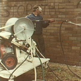 Council employee cleaning graffiti