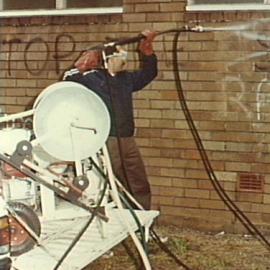 Council employee cleaning graffiti