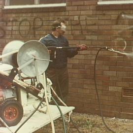 Council employee cleaning graffiti