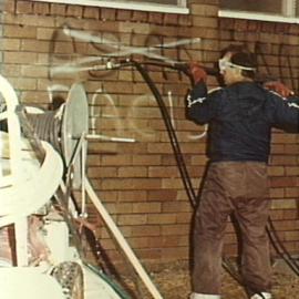 Council employee cleaning graffiti