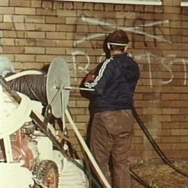 Council employee cleaning graffiti