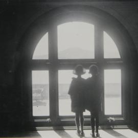 Adele Mildenhall and friend looking out a window in Parliament House, Canberra, 1925