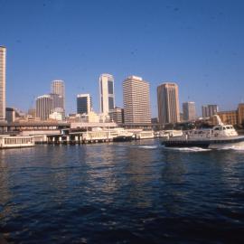 Ferry leaving wharf at Circular Quay and northern Sydney CBD skyline, 1980s
