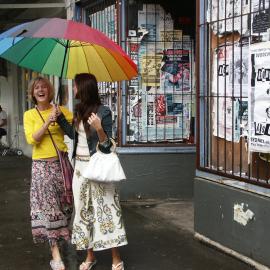 Friends holding an umbrella outside an abandoned shopfront, Glebe Point Road Glebe, 2004