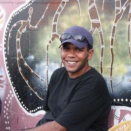 Young man sitting in front of the mural on Eveleigh Street Redfern, circa 2003