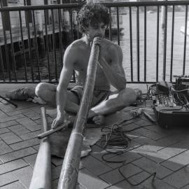 Indigenous busker playing a didgeridoo near ferry wharf, Circular Quay Sydney, 2001