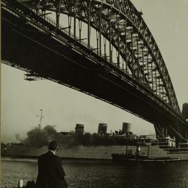 Man sits under Sydney Harbour Bridge watching passenger ship, circa 1940s